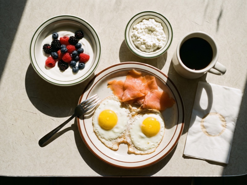Overhead view of a breakfast with fried eggs, smoked salmon, Greek yogurt with berries and cottage cheese